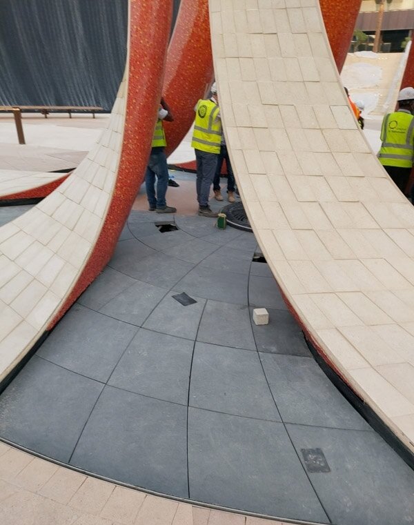 Montage des Steinbodens um die Bogen-Skulptur auf der Expo 2020