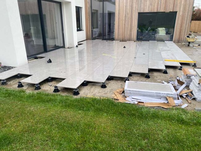 Aufbau einer Stelzlager Terrasse auf dem Boden mit Platten auf der Terrassenfläche im Hausgarten