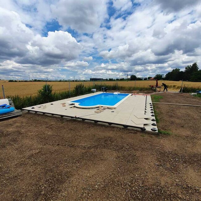 Ein Schwimmbad, das auf dem Boden mit Platten gebaut wird, die auf höhenverstellbaren Stelzlagern verlegt sind.