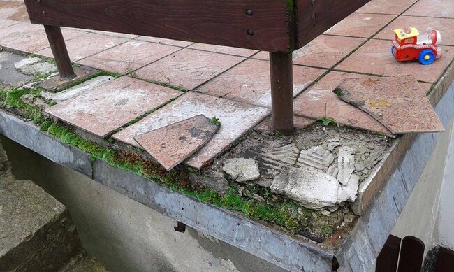 Abplatzende und bröckelnde Platten auf einer traditionell verklebten Terrasse