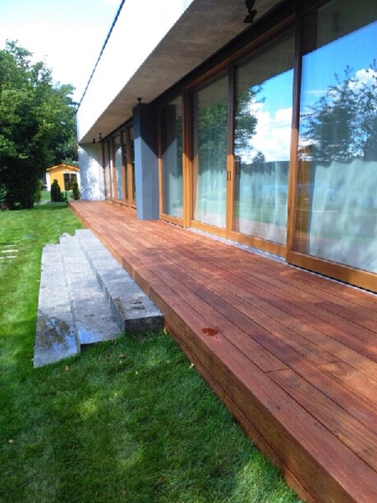 Gestaltung einer Terrasse mit Feinsteinzeugplatten, Rattansesseln und Pflanzen.