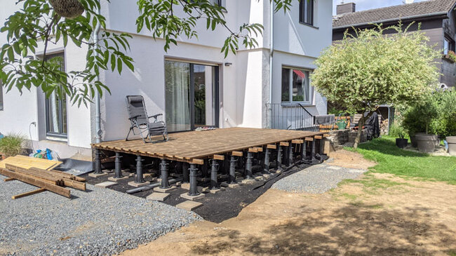 Aufbau einer Holzterrasse auf hohen verstellbaren Stelzlagern am Haus