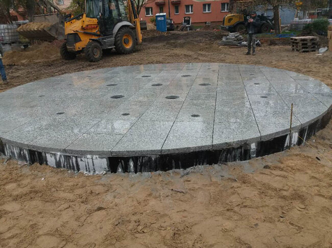 Budowa okrągłej fontanny miejskiej z szarych płyt granitowych na placu
