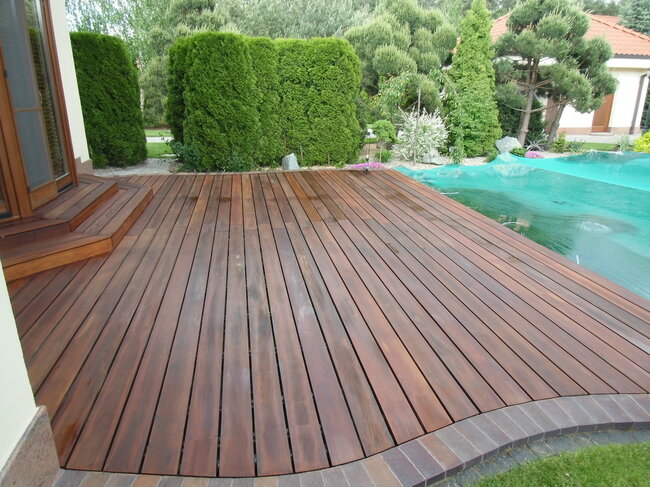 Fertigstellung der Gartenterrasse aus Holzplanken mit Einfassung aus Pflastersteinen.