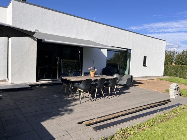 Moderne Terrasse mit Betonplatten an einem weißen Haus