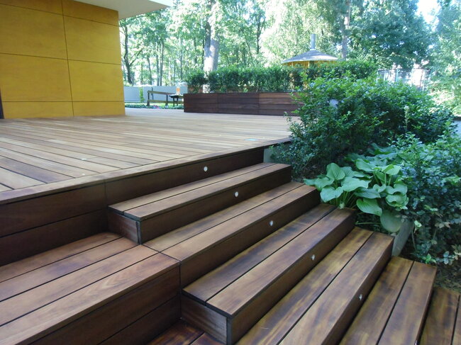 Holzterrasse mit Treppen und Beleuchtung im Garten