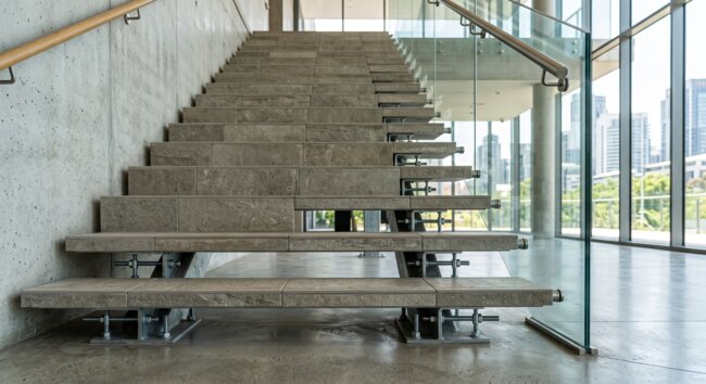 Moderne Steintreppen und Glasgeländer im industriellen Innenraum
