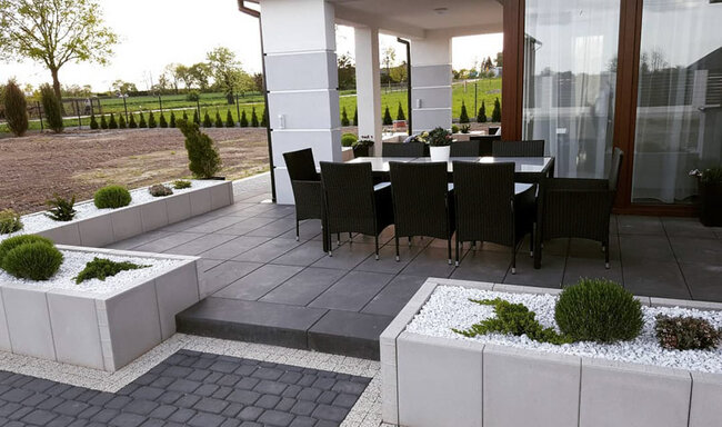 Moderner Stelzlager Terrasse mit dunklen Platten und Gartenmöbeln