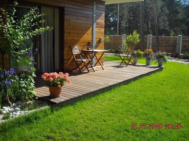 Holzterrasse im Garten mit Terrassenmöbeln und Blumen