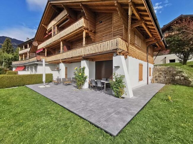 Stelzlager Terrasse mit dunklen Feinsteinzeugplatten bei einem Holzhaus im Alpenstil