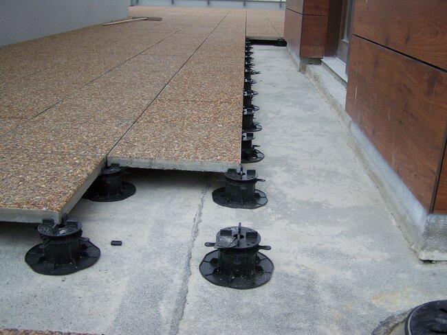 Terrassenplatten mit Zuschlagstoff auf schwarzen verstellbaren Stelzlagern