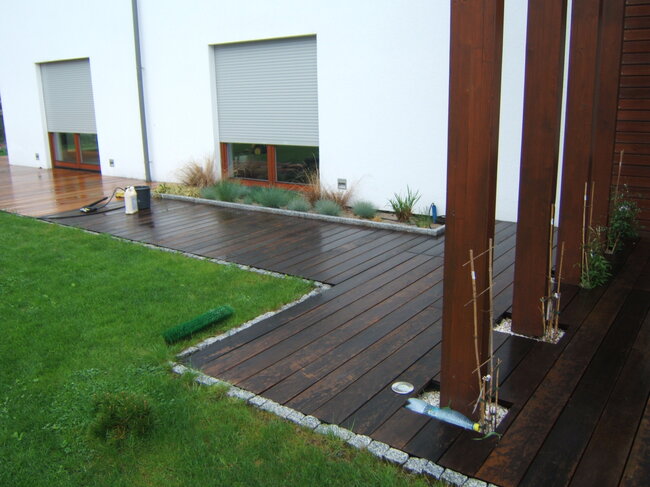 Dunkle Holzterrasse am Haus während der Reinigung und Ölung