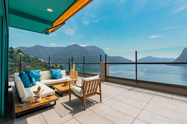 Moderni elegancki Stelzlager Terrasse mit Loungemöbeln und Blick auf den See
