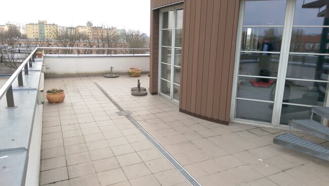 Große Terrasse mit Platten und Linienentwässerung auf dem Dach des Gebäudes