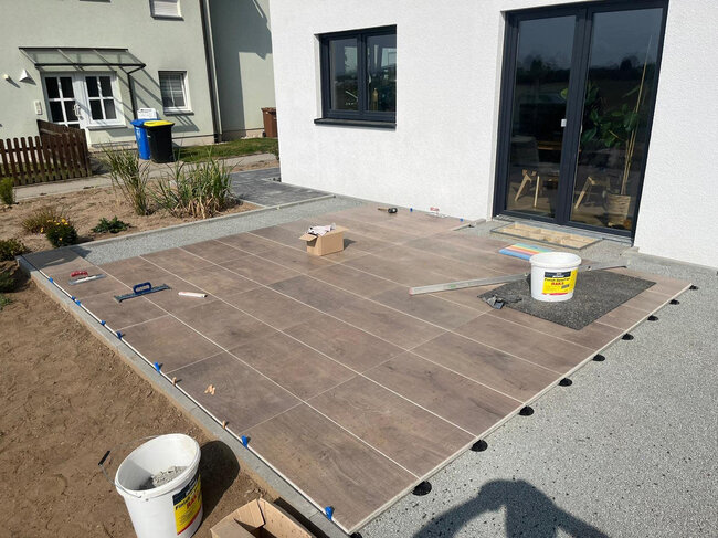 Aufbau einer Stelzlager Terrasse mit Holzoptik-Fliesen am Haus