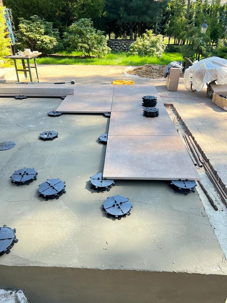 Verlegung von Terrassenplatten auf schwarzen Grundplatten im Garten