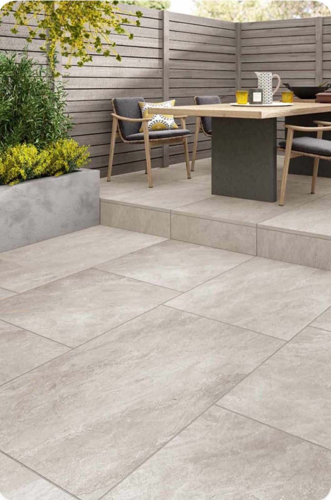 Zweistöckige Terrasse aus hellen Feinsteinzeugplatten mit Gartenmöbeln