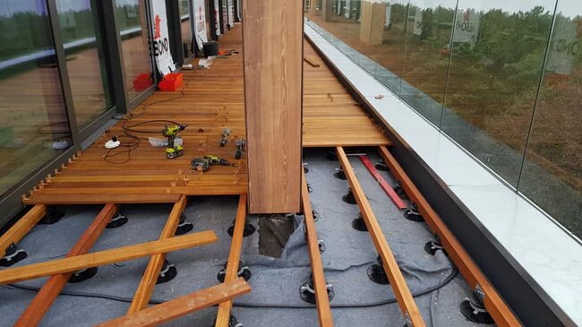Terasse mit Stelzlager aus exotischen Dielen auf Balken während der Montage.
