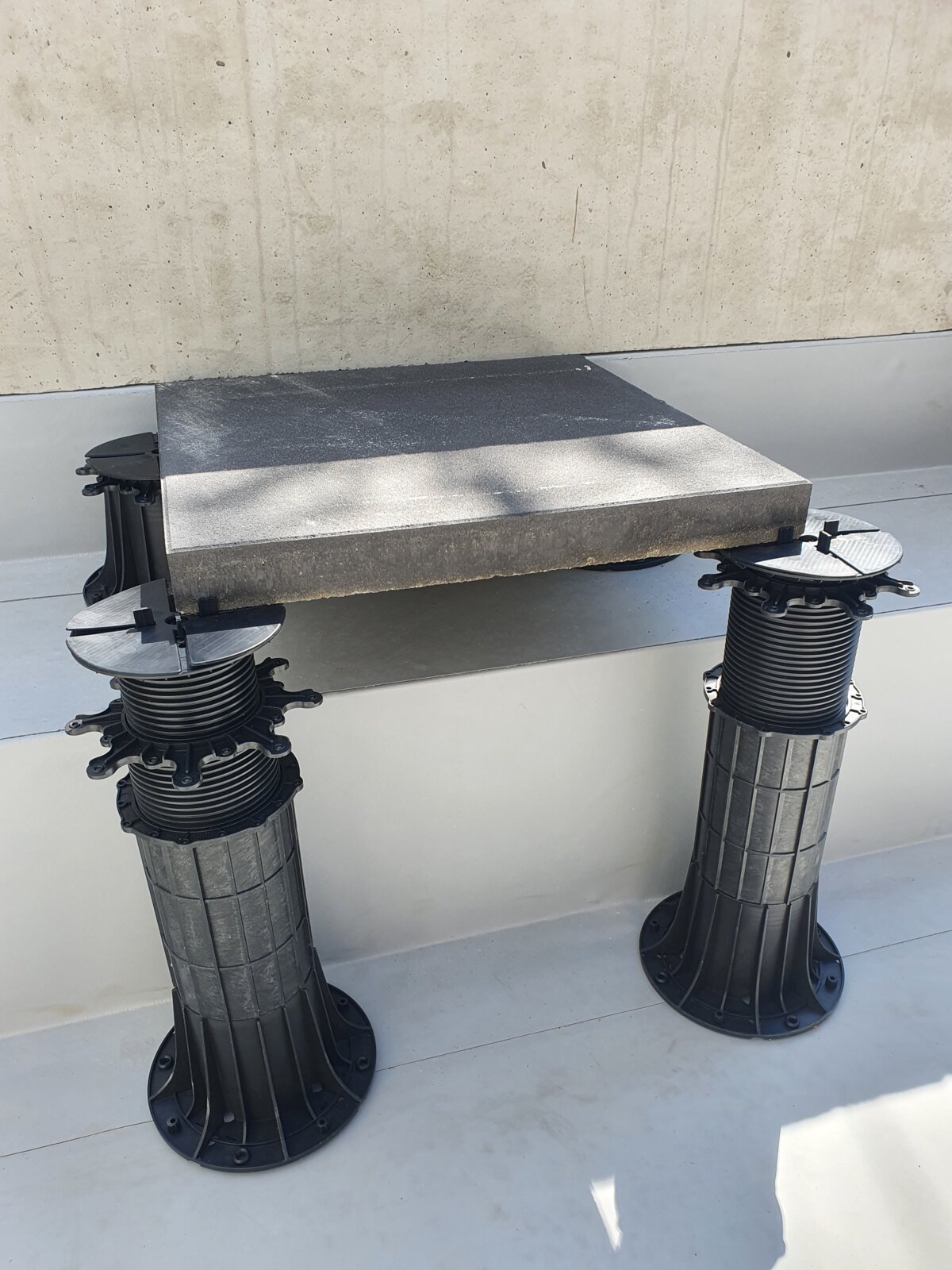 *Foto eines Stelzlager-Terrassendachs mit Betonplatten und höhenverstellbaren STANDARD-Stelzlagern.