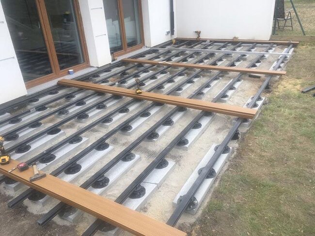 Verstellbare Stelzlager auf Betonplatten auf dem Boden verlegt und Terrassendielen verlegt