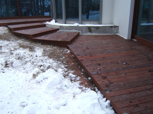 Holztreppe und exotische Terrasse im Winter mit Schnee bedeckt.