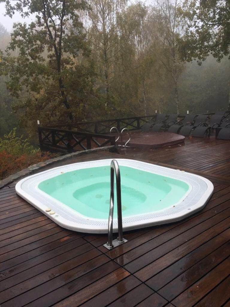 Wbudowane jacuzzi ogrodowe na drewnianym tarasie w otoczeniu lasu .
