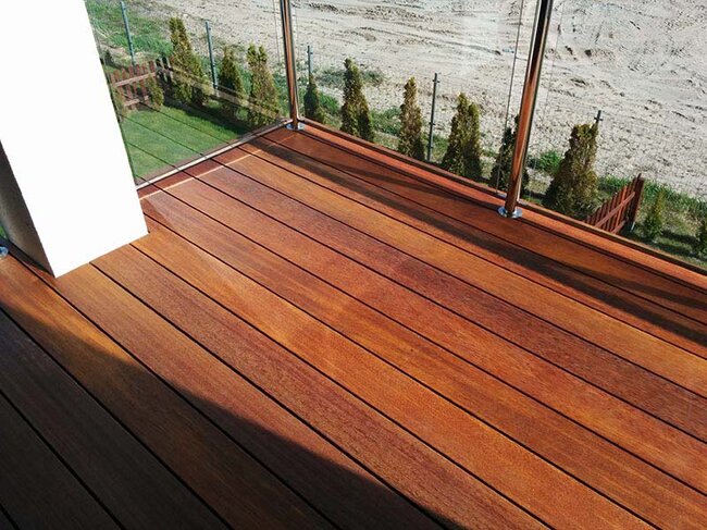 Balkon aus exotischem Holz mit Glasgeländer.