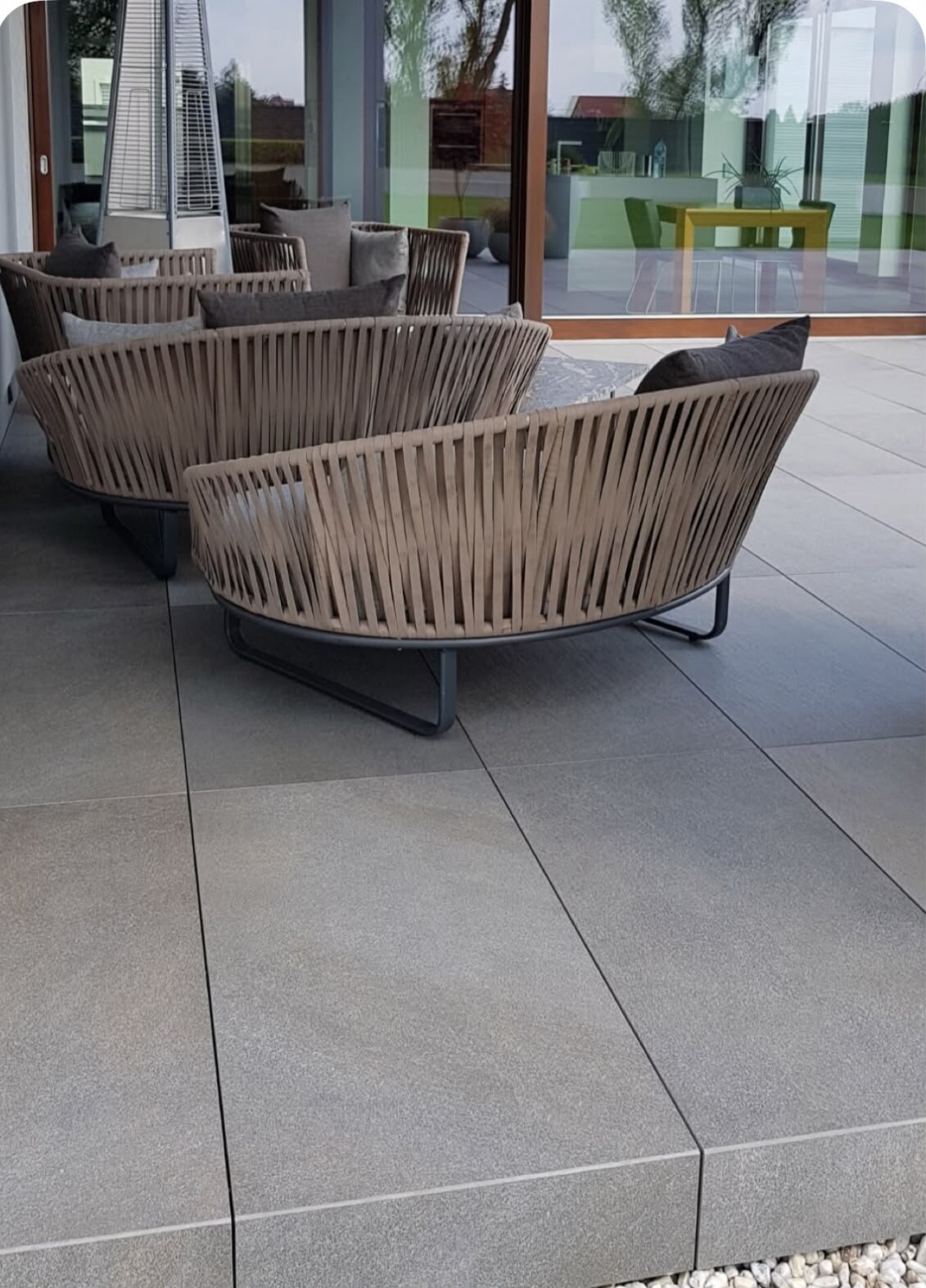 Modernistyczny taras z płyt gresowych wyposażony w plecione meble ogrodowe