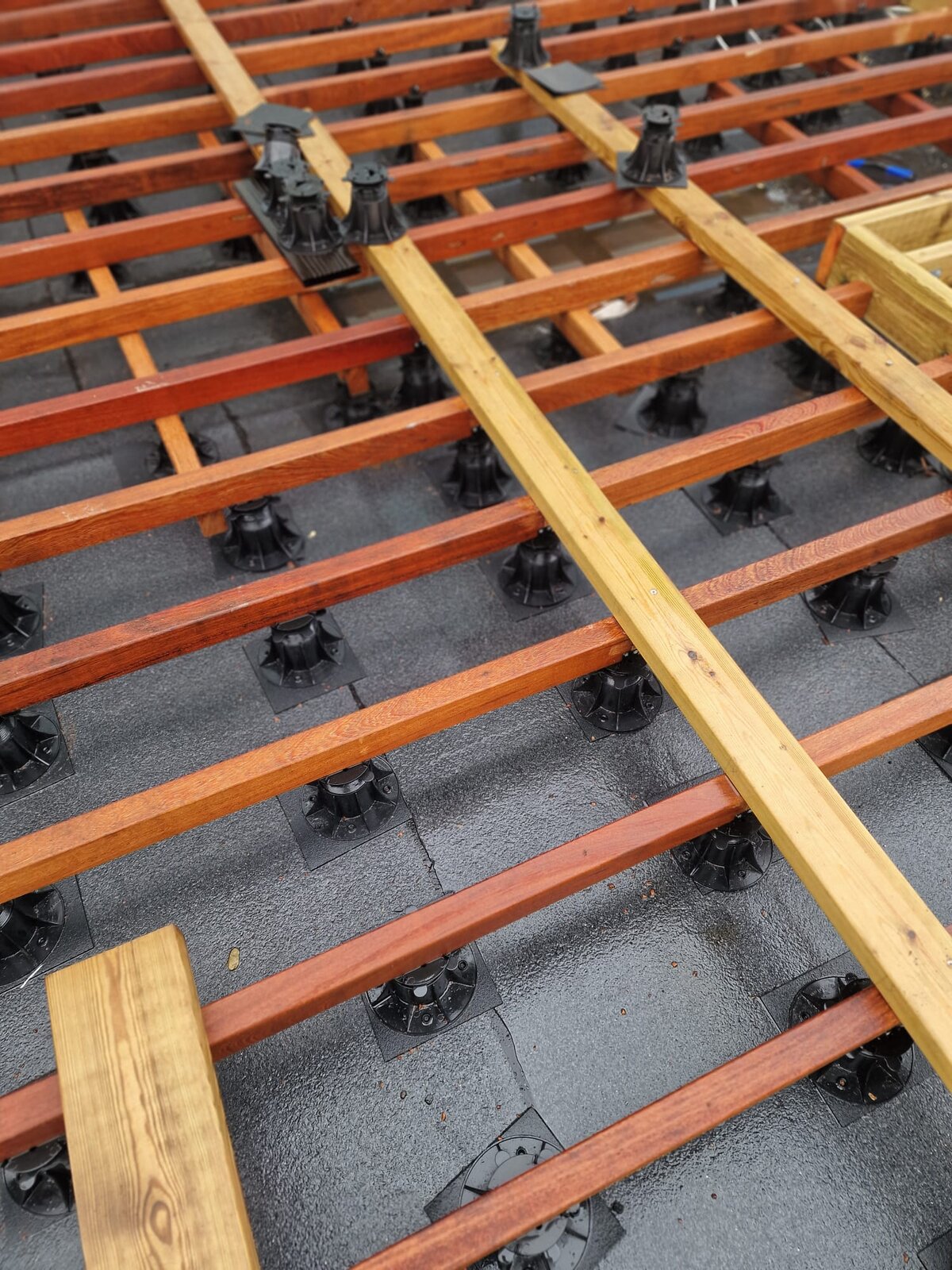 Montage der Unterkonstruktion einer Holzterrasse auf höhenverstellbaren Stelzlagern.