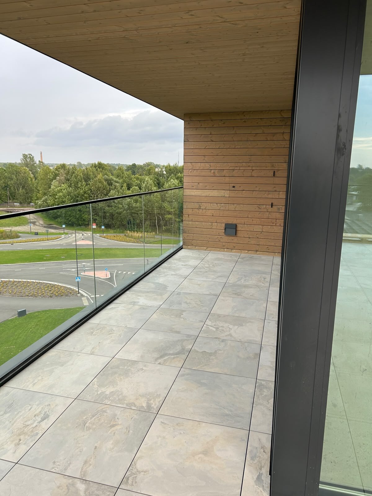 Moderner Balkon mit grauen Terrassenplatten mit Blick auf einen Fluss und eine Bogenbrücke