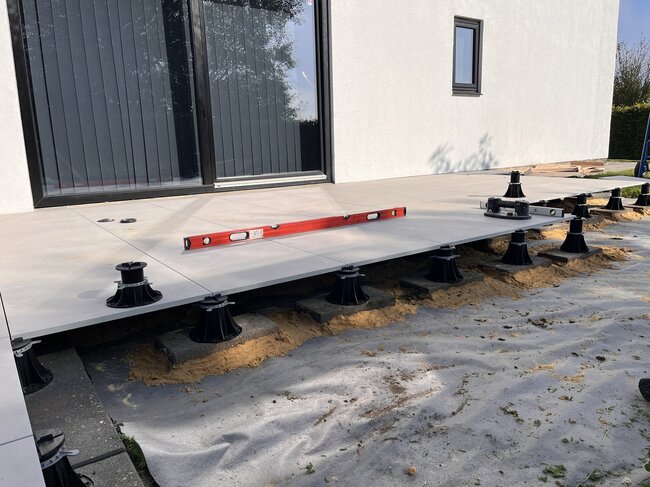 Installation von erhöhten Terrassenplatten im Außenbereich mit höhenverstellbaren Terrassen Stelzlagern.