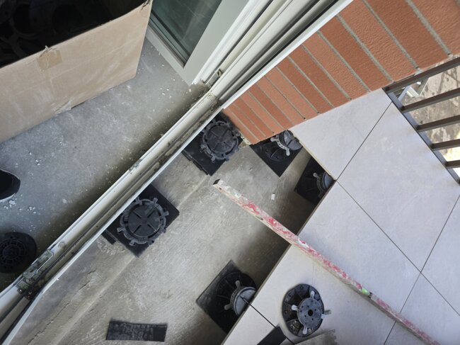 Installation eines erhöhten Boden-Stelzlagersystems für die Verlegung von Fliesen auf einem Balkon entlang der Kante.