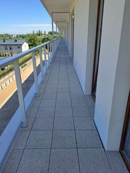 Fertiger langer Außen-Terrassenboden mit Terrassenplatten in Betonoptik und weißen Geländern.