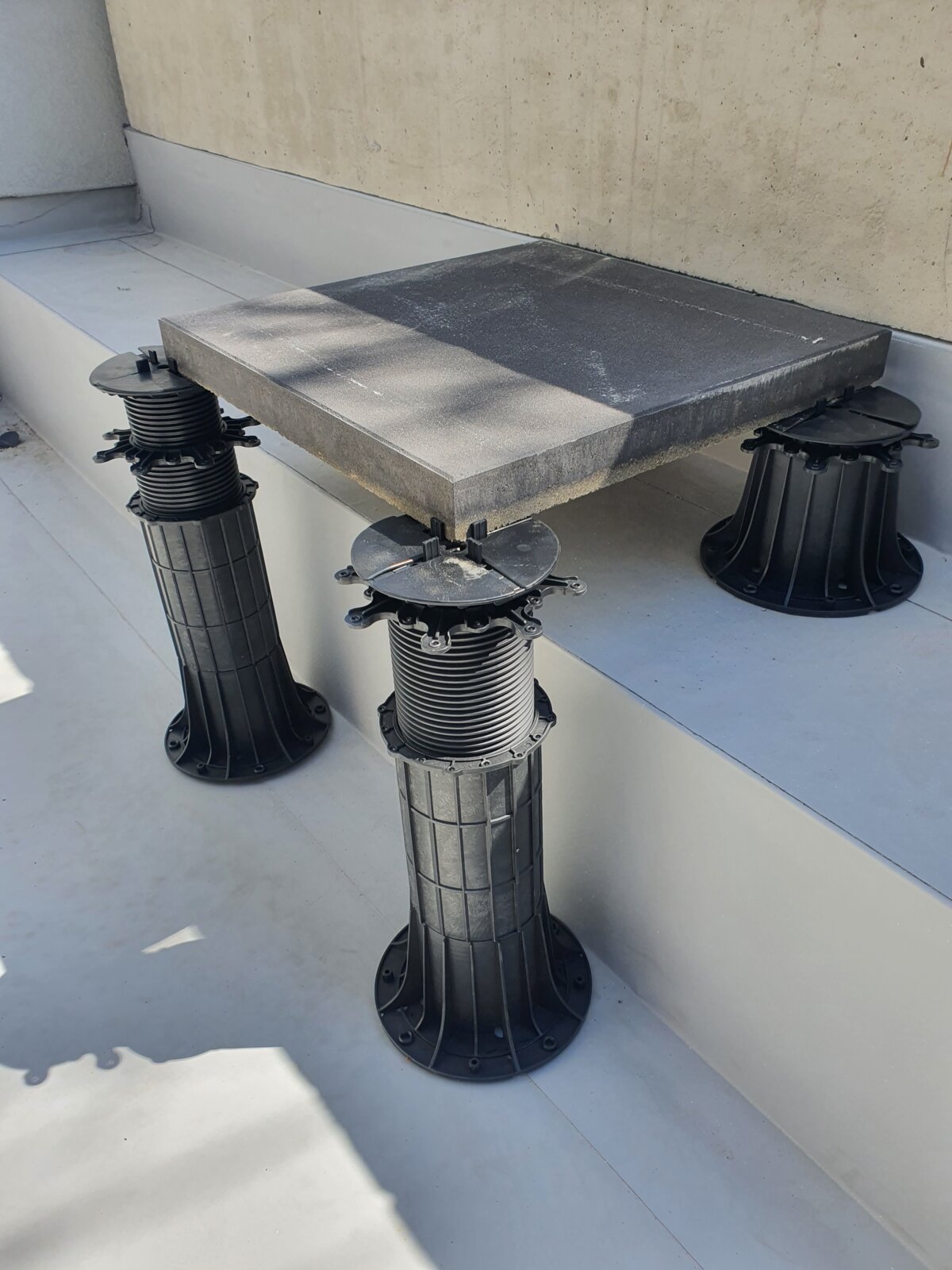 Quadratische Betonplatte montiert auf höhenverstellbaren Kunststoff-Stelzlagern.