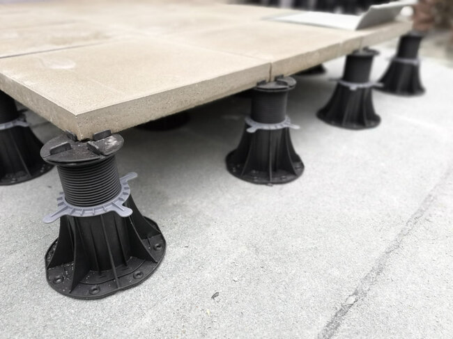 System höhenverstellbarer Terrassen-Stelzlager, das Außenbetonplatten während der Installation trägt.