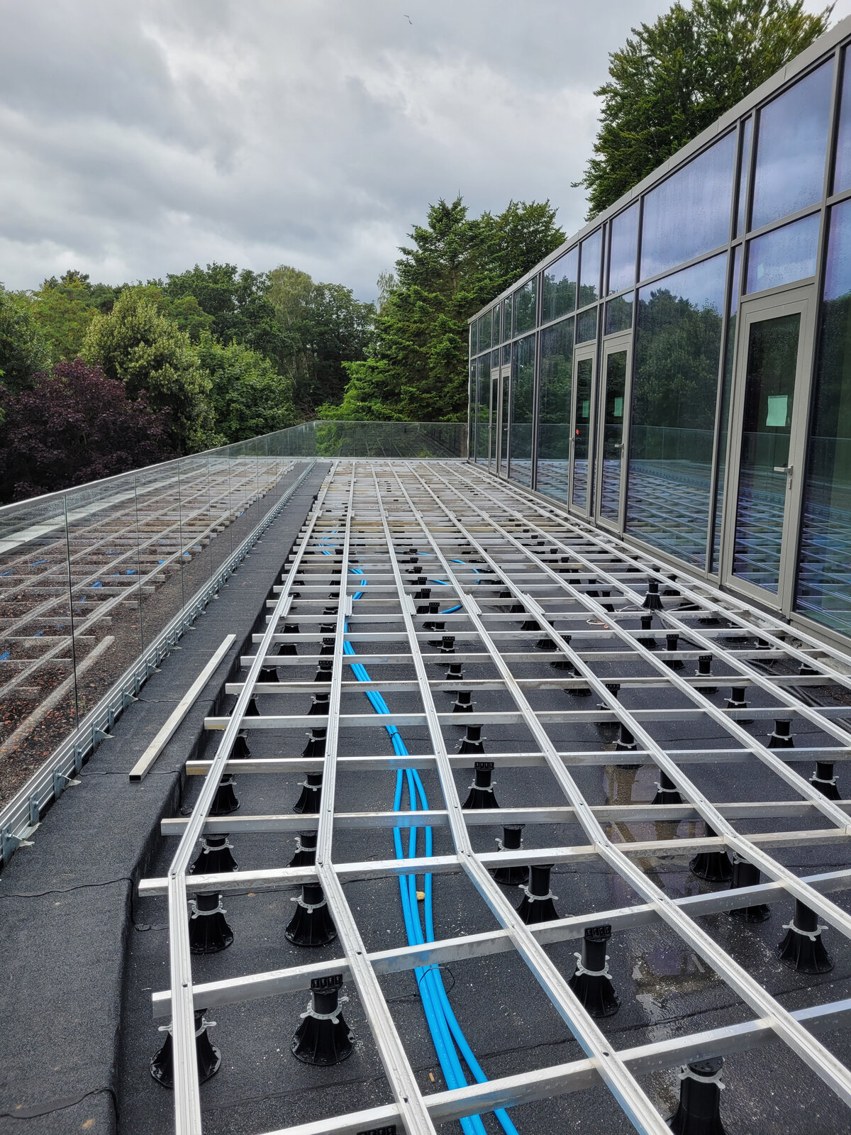 Aluminium-Balkenrahmen montiert auf höhenverstellbaren Kunststoff-Terrassen-Stelzlagern für den Außenbereich.