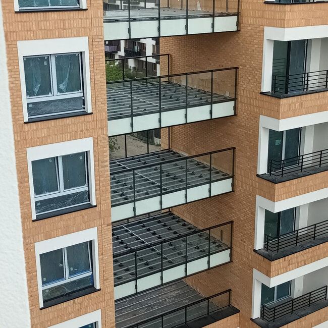 Mehrgeschossige Balkon-Unterkonstruktionen mit Aluminiumbalken, die auf höhenverstellbaren Terrassen-Stelzlagern aus Kunststoff ruhen.
