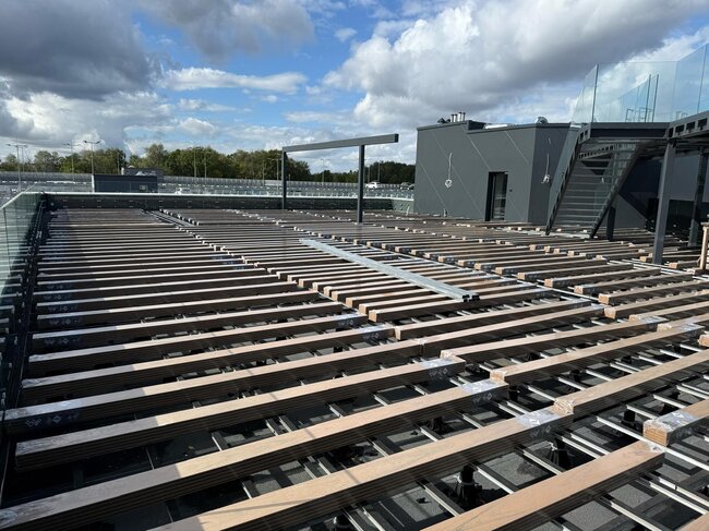 Aluminium-Balkenunterkonstruktion auf Stelzlagern, die unter einer modernen Dachterrasse montiert wird.