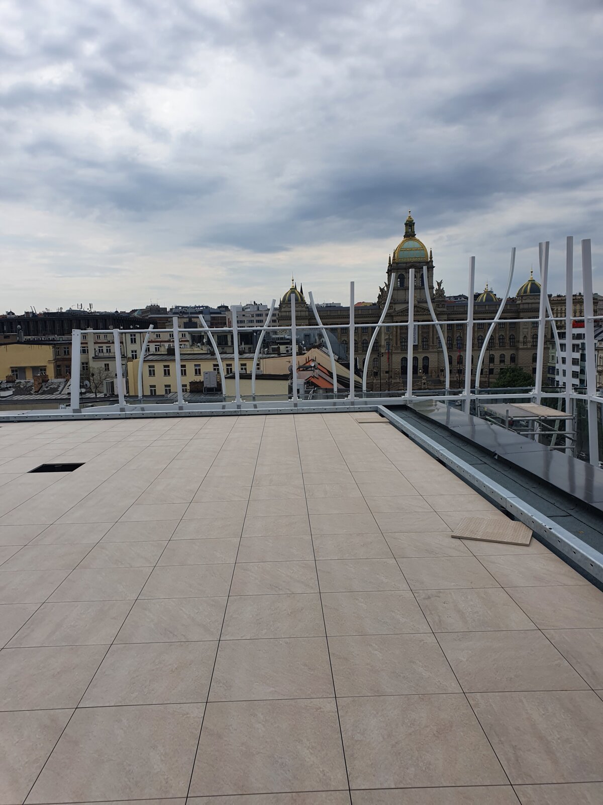 Dachterrasse mit installierten Außenbodenplatten aus Porzellan mit Blick auf historische Stadtgebäude.