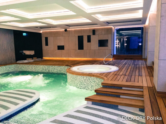 Erhöhter Holzdeck über einem Innenpool, installiert mit höhenverstellbaren Stelzlagern.