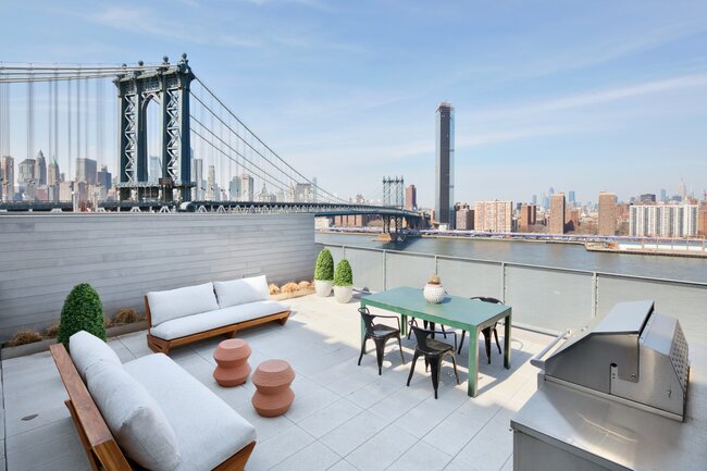 Dachterrasse mit Gartenmöbeln, Grill und Blick auf die Manhattan Bridge sowie die Skyline von New York.