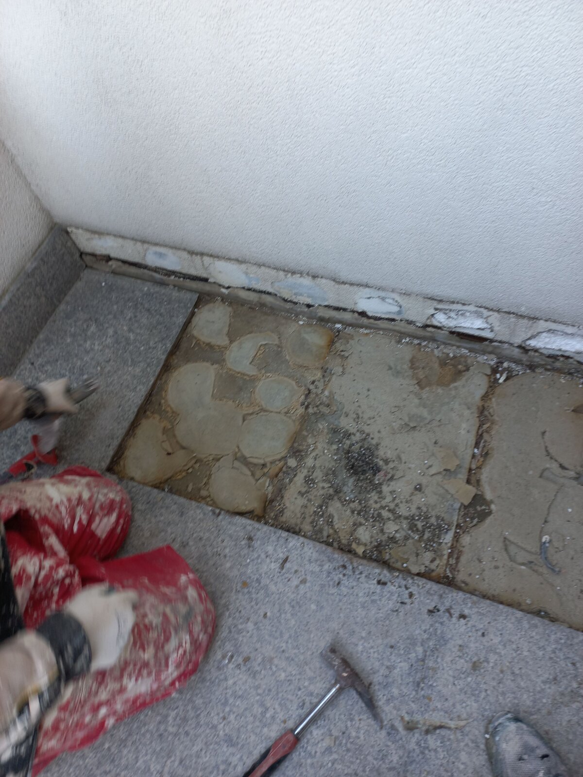 Arbeiter entfernt beschädigte Steinplatten und Klebemörtel bei der Terrassenreparatur.