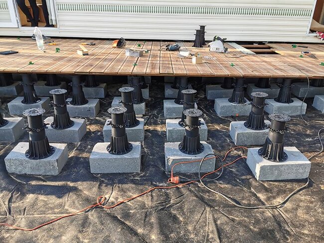 Höhenverstellbare Terrassen-Stelzlager, montiert auf Betonblöcken, die eine Holzterrassenkonstruktion tragen.