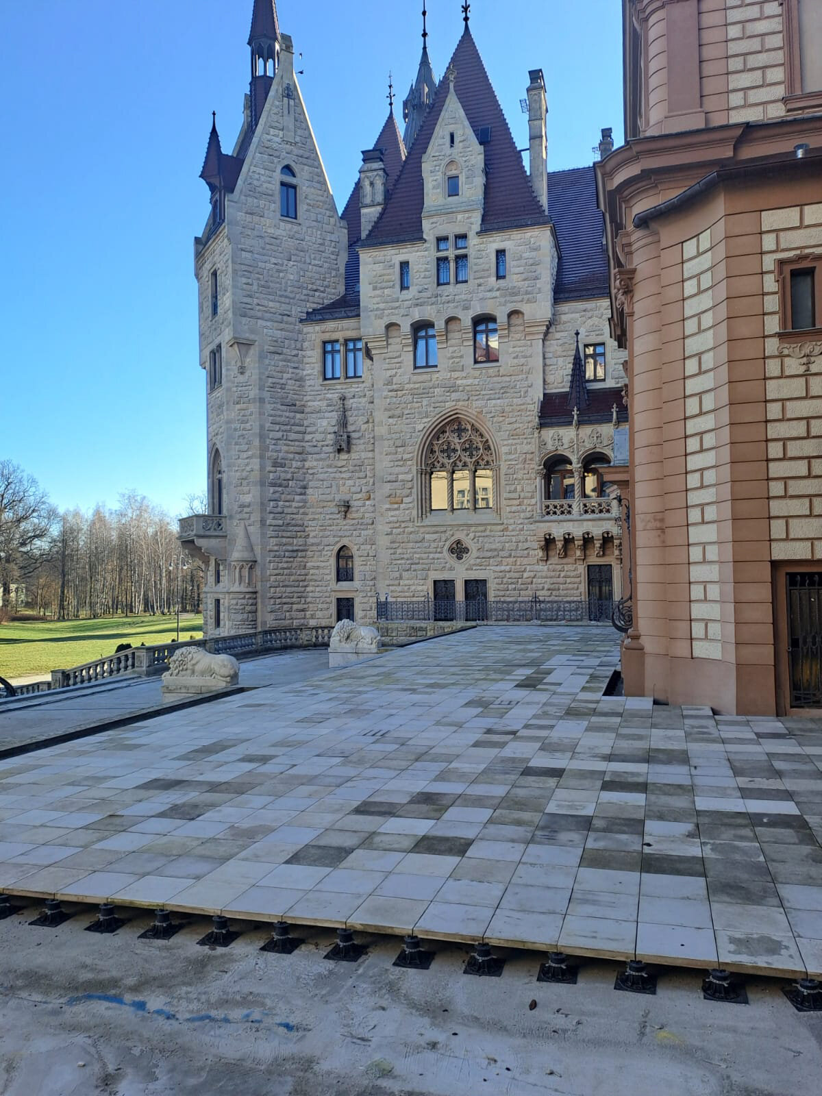 Erhöhte Steinplatten-Terrasse, installiert auf höhenverstellbaren Terrassen-Stelzlagern vor einem historischen Gebäude.