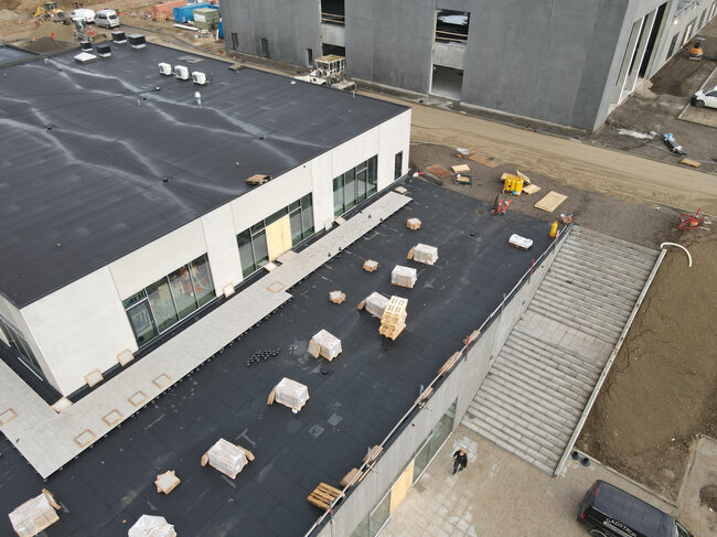 Luftaufnahme eines Flachdachs eines Gebäudes während der Bauphase mit montierten Terrassenplatten und Stelzlagern.