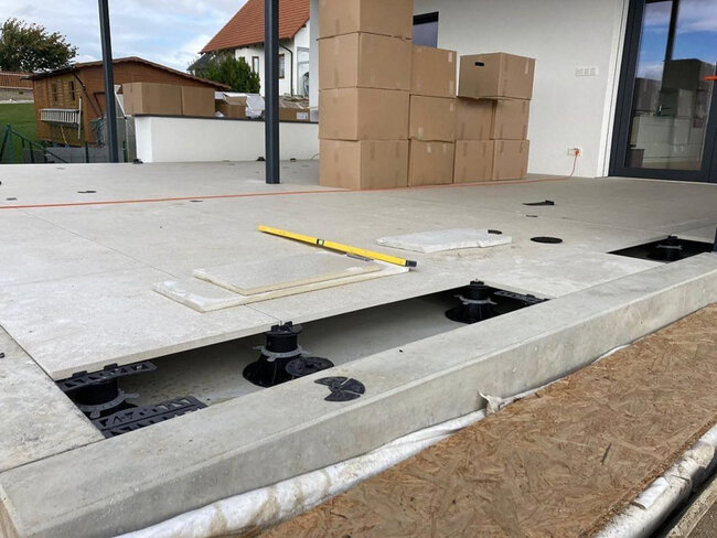 Montage von Platten auf einer erhöhten Terrasse mit höhenverstellbaren Stelzlagern auf einer Außenpatio.