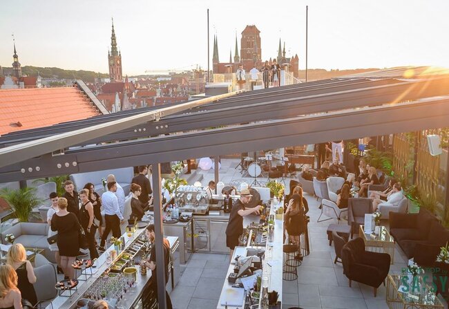 Gewerbliche Dachterrasse, errichtet auf einem System höhenverstellbarer Terrassen-Stelzlager während einer Veranstaltung bei Sonnenuntergang.