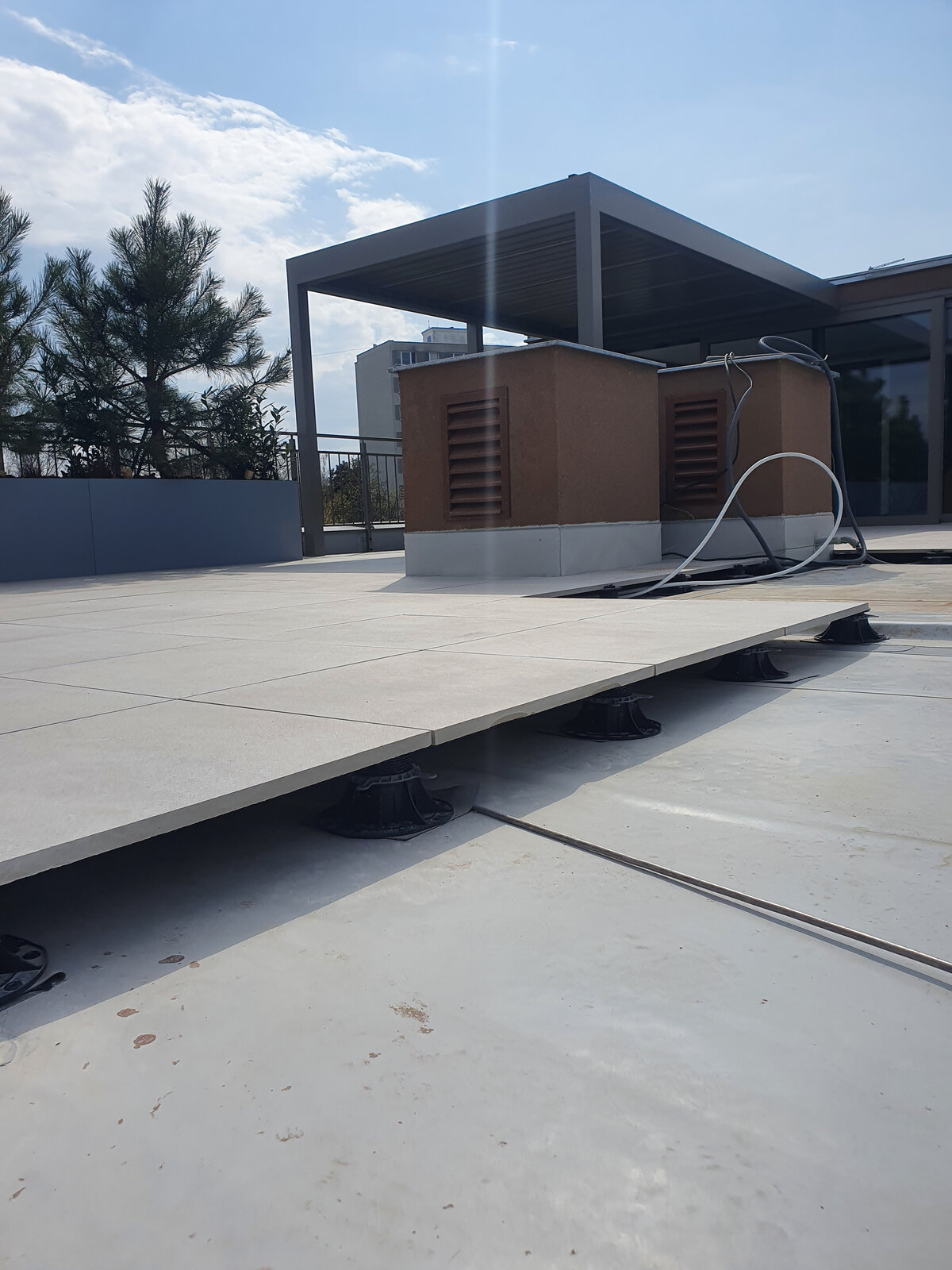 System höhenverstellbarer Stelzlager, das angehobene Terrassenplatten im Außenbereich trägt.
