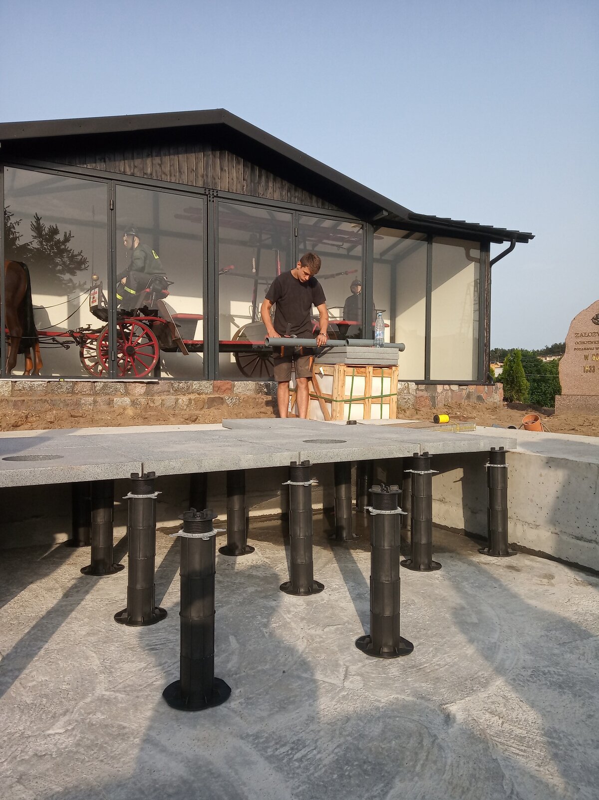 Montage hoher höhenverstellbarer Stelzlager, die Steinplatten in einem erhöhten Bodensystem um einen Außenbrunnen tragen.